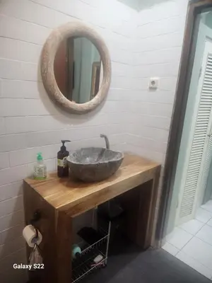 a bathroom with a stone sink and a mirror at Jimmy's Hideaway at Mulia Cottages in Seminyak