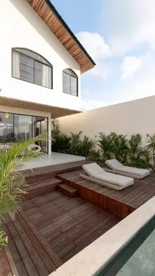 a backyard with a wooden deck next to a house at Casa Amani 3BR Mediterranean w Pool Near Seminyak in Kerobokan