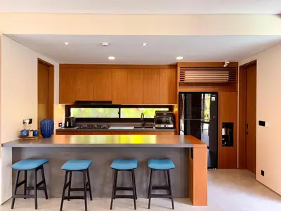 a kitchen with a large island with blue bar stools at Villa Daun Emas in Jimbaran