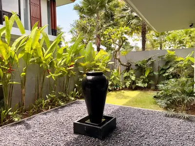 a black vase sitting on the ground in a garden at Villa Daun Emas in Jimbaran