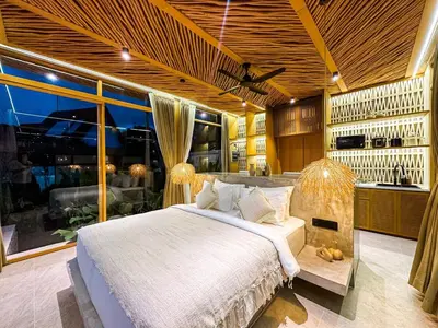 a bedroom with a large bed and a kitchen at Desa Hut - Tropical Haven with Ricefield View near Seminyak in Kerobokan