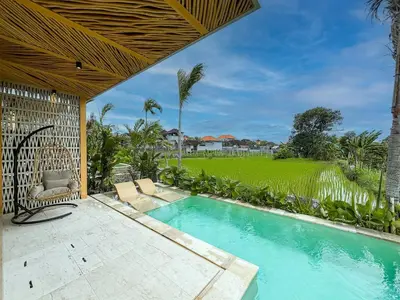 a swimming pool in a villa with a garden at Desa Hut - Tropical Haven with Ricefield View near Seminyak in Kerobokan