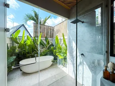 a bathroom with a tub and a glass shower at Desa Hut - Tropical Haven with Ricefield View near Seminyak in Kerobokan