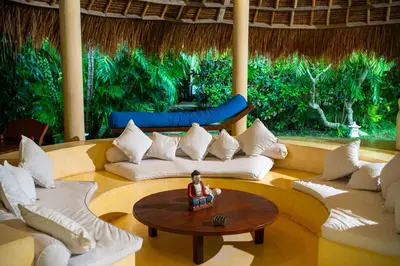 a living room with white couches and a table at Nomadic Resort Bali in Canggu