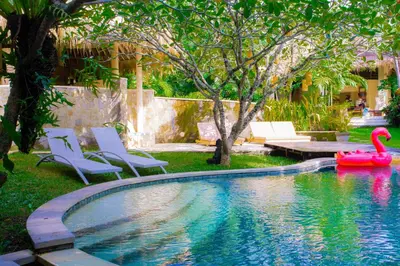 a swimming pool with a pink swan in a yard at Nomadic Resort Bali in Canggu