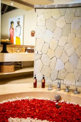 a bathroom with a sink with red flowers on the counter at Nomadic Resort Bali in Canggu