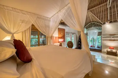 a bedroom with a large white bed with curtains at Nomadic Resort Bali in Canggu