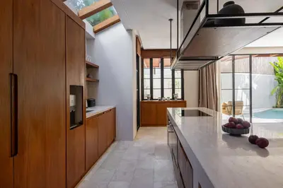a kitchen with wooden cabinets and a counter top at Nila Villa Berawa Canggu in Canggu