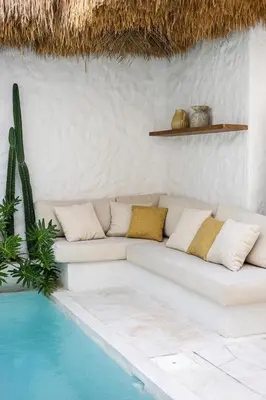 a white couch sitting next to a swimming pool at Nila Villa Berawa Canggu in Canggu