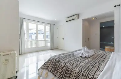 a white bedroom with a bed and a large window at Seminyak Luxe Villa Near Beach, Breakfast Concierge in Seminyak