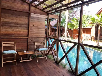 a pergola with two chairs and a table next to a pool at Cozy Lagoon Bungalows & Pool in Nusa Dua
