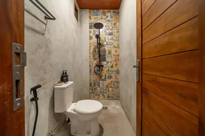 a bathroom with a toilet and a wooden door at 2BR Private tropical villas in Jimbaran in Jimbaran