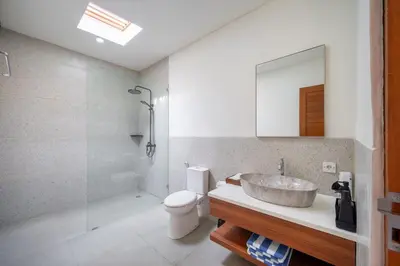 a bathroom with a sink and a toilet and a mirror at Modern 2BR Umalas Villa with Private Pool & Garden in Kerobokan