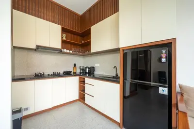 a kitchen with white cabinets and a black refrigerator at Modern 2BR Umalas Villa with Private Pool & Garden in Kerobokan