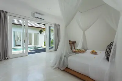 a white bedroom with a bed with a canopy at Adhya Villa by GenuineHost in Kerobokan