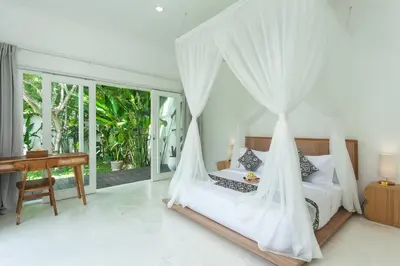 a bedroom with a bed with a mosquito net at Adhya Villa by GenuineHost in Kerobokan