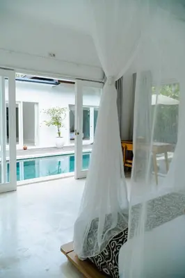 a bedroom with a bed with a mosquito net at Adhya Villa by GenuineHost in Kerobokan