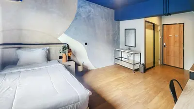 a bedroom with a white bed and a mirror at Rukita Sunset Road Seminyak in Seminyak