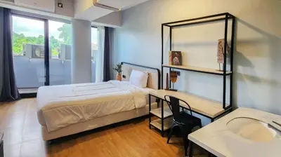 a bedroom with a bed and a desk and a mirror at Rukita Sunset Road Seminyak in Seminyak