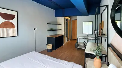 a bedroom with a bed and a desk and a sink at Rukita Sunset Road Seminyak in Seminyak