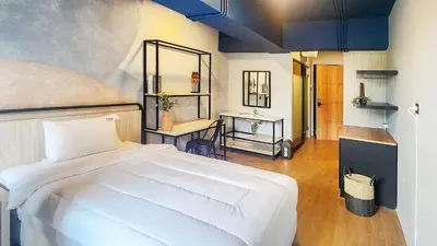 a bedroom with a white bed and a desk at Rukita Sunset Road Seminyak in Seminyak