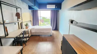 a bedroom with a bed and a desk and a table at Rukita Sunset Road Seminyak in Seminyak