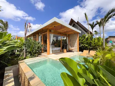 a house with a swimming pool in front of a house at Desa Hut - Serene Tropical Hideaway Rice Fields near Seminyak in Kerobokan