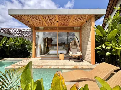 a house with a swimming pool next to a resort at Desa Hut - Serene Tropical Hideaway Rice Fields near Seminyak in Kerobokan