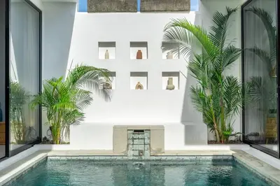 a pool in the middle of a building with palm trees at Harmony A29-Peaceful 1BR Retreat in Seminyak