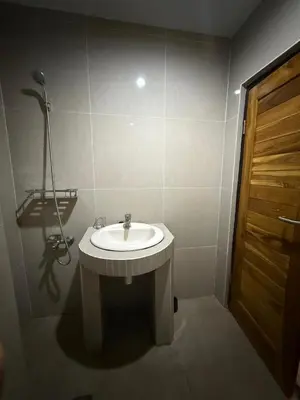 a bathroom with a white sink and a wooden door at OKIE HOUSE HOTEL Poppies2 3 min from Kutabeach in Legian