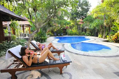 two women laying in chairs near a swimming pool at Jepun Bali Hotel in Kuta