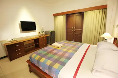 a bedroom with a bed and a desk with a television at Jepun Bali Hotel in Kuta