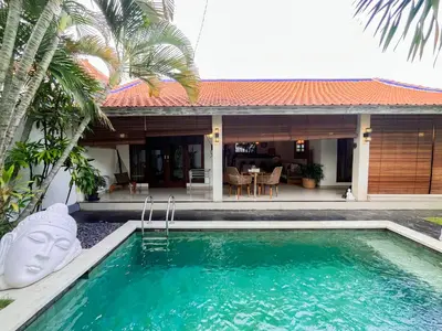 a villa with a swimming pool in front of a house at Villa Sayang 1 Seminyak in Seminyak