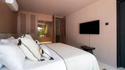 a bedroom with a white bed with a flat screen tv at Villa Dreamora by Villa Finder in Seminyak