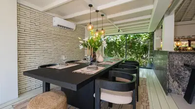 a dining room with a black table and black chairs at Villa Dreamora by Villa Finder in Seminyak
