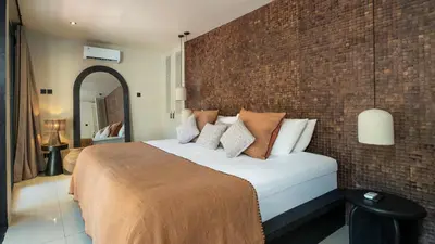 a bedroom with a bed and a brick wall at Villa Dreamora by Villa Finder in Seminyak