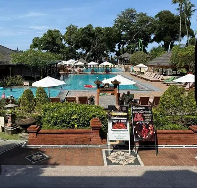 a resort with a swimming pool and a resort sign at Jayakarta Bali Apartments in Seminyak