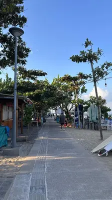 a street with trees and a person walking down a sidewalk at Jayakarta Bali Apartments in Seminyak