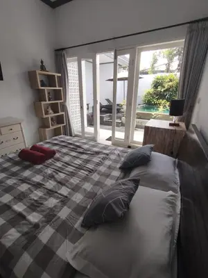 a bedroom with a bed with pillows and a window at sari uma in Seminyak
