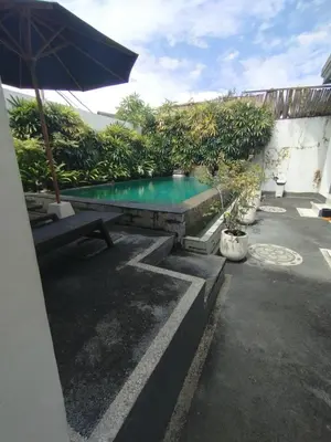 a swimming pool with a table and an umbrella at sari uma in Seminyak