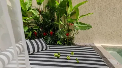 a bench with green apples on it next to a pool at Suom Apartments and Villas Canggu in Canggu