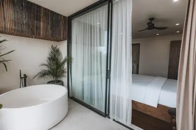 a bathroom with a bath tub and a bed at Suom Apartments and Villas Canggu in Canggu