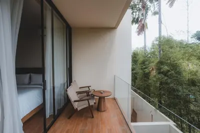 a room with a balcony with a bed and a table at Suom Apartments and Villas Canggu in Canggu