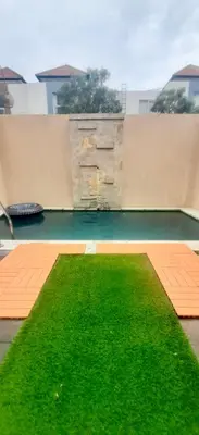 a yard of green grass on a building at Uma Mari Villa Seminyak in Seminyak