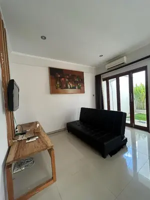 a living room with a black couch and a table at Uma Mari Villa Seminyak in Seminyak
