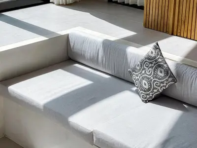 a white couch with a pillow sitting on a patio at Desa Hut - 2BR Tropical Ricefield Villa near Seminyak in Kerobokan