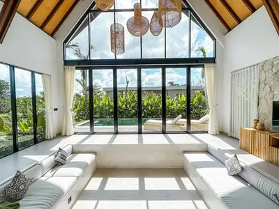 a living room with large windows and a large couch at Desa Hut - 2BR Tropical Ricefield Villa near Seminyak in Kerobokan