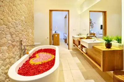 a bathroom with a large tub filled with red flowers at Daiva Comfortable 1 BR Private Pool Villa in Jimbaran