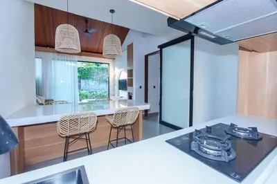 a kitchen with a counter and chairs in a room at Rama Villa Umalas in Kerobokan