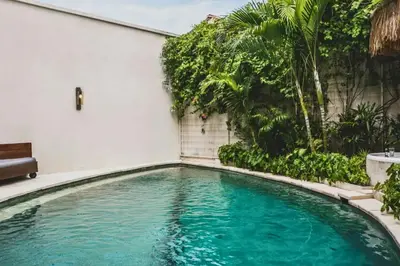 a swimming pool in front of a building with trees at Charity Stunning Grand 1 BR Pool Villa With Jacuzzi in Seminyak